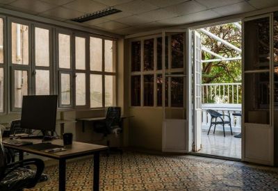 Large office space with patterned tile floors and access to a sunny balcony.