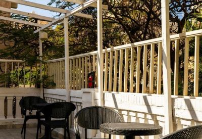 Outdoor patio with black wicker furniture under a white pergola.