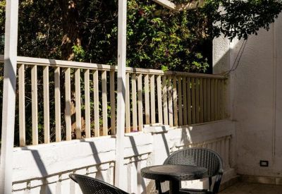 Sunny balcony seating area with two chairs and a small table.