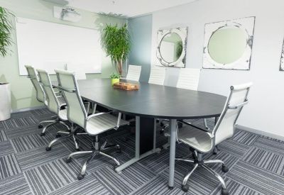 Boardroom with an oval black table and sleek white mesh chairs.