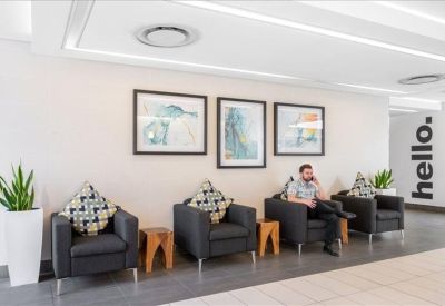 Modern wooden reception desk with white walls and sleek pendant lights.
