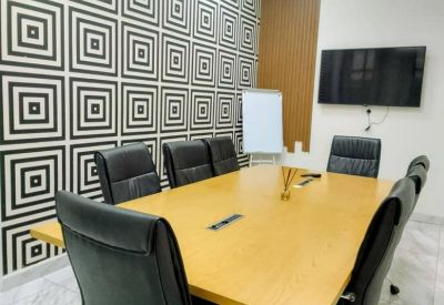 Professional conference room with a wooden table, black leather chairs, and a geometric pattern accent wall.
