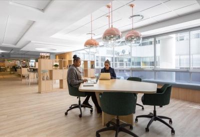 Modern coworking area with a wooden table, designer lighting, and floor-to-ceiling windows.