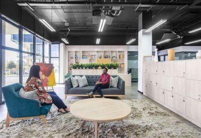 Modern reception desk with a textured wall and comfortable blue armchairs.