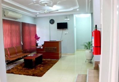 Bright reception area with a wooden front desk, brown rug, and indoor plants.
