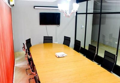 Modern conference room with a long light-wood table and black mesh chairs.