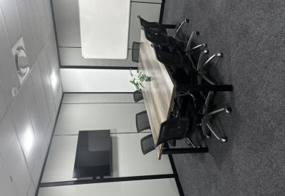 Meeting room featuring a long wooden table, black mesh chairs, and a wall-mounted television.