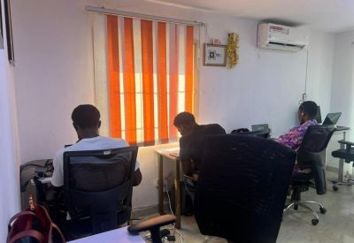 Quiet office room with individual workstations and orange striped window blinds.