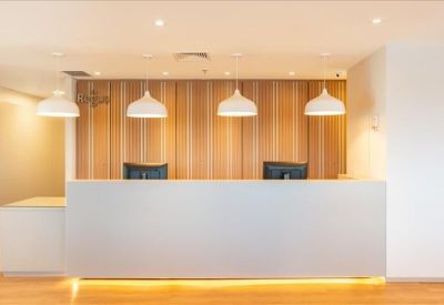 Spacious reception area with a white front desk and wood panelled backdrop.