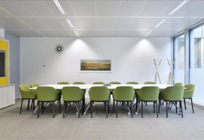 Meeting room with green chairs and a minimalist landscape painting.