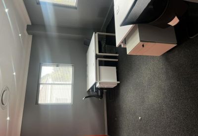 Workspace with a white L-shaped desk and grey feature wall.