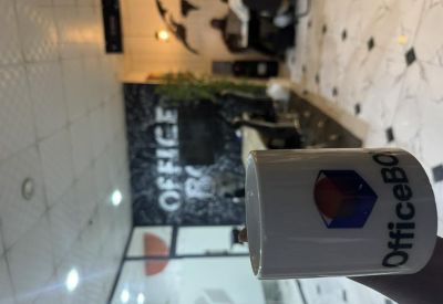 Branded coffee mug in a modern reception area with decorative wall graphics and indoor plants.