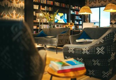 Lounge area with patterned armchairs, bookshelves, and warm overhead lighting.