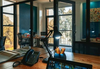Modern private office with wood desks, glass partitions, and a desk lamp.