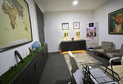 Executive office with a world map wall mural, black storage cabinetry, and grey visitor armchairs.