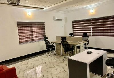 Modern workspace with multiple workstations and sleek white desks under warm lighting.