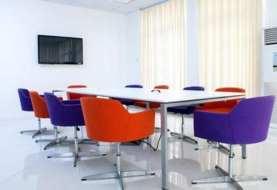 Bright conference room featuring a white table and colorful orange and purple chairs.