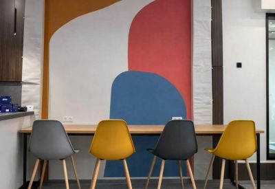 Communal dining area with colorful abstract mural and mustard yellow chairs.