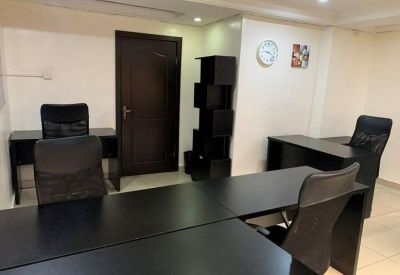 Modern workspace with black desks, mesh chairs, and a geometric shelving unit.
