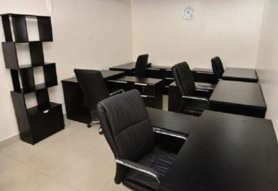 Cozy workspace featuring several L-shaped desks and black leather ergonomic chairs.