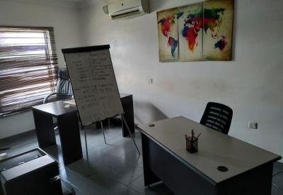 Private office featuring two desks, a whiteboard, and a colorful world map wall art.