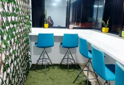 Narrow breakout zone with turquoise bar stools, green faux-grass flooring, and a leafy trellis wall.