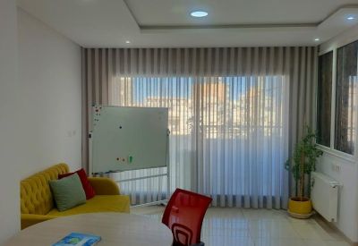Small meeting area with a round table, red chair, yellow sofa, and a mobile whiteboard.
