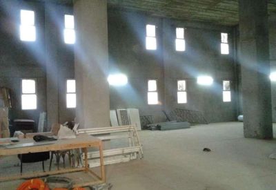 Large open-plan concrete room with multiple small windows and light beams illuminating the floor.