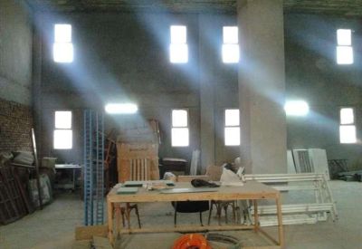 Industrial space featuring high ceilings, concrete pillars, and bright square windows.