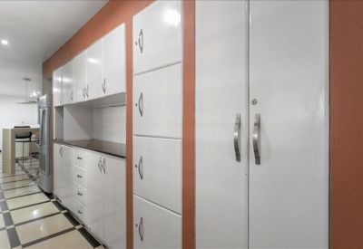 Modern communal kitchen area with sleek white cabinetry and terracotta-colored walls.