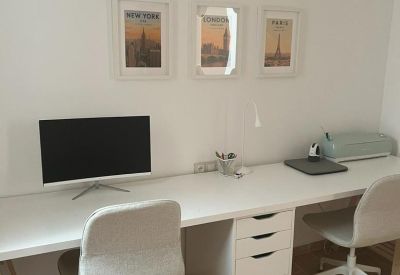 Long shared workspace with dual chairs, a monitor, and integrated storage drawers.