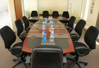 Professional boardroom with a long wood table, black chairs, and bottled water service.