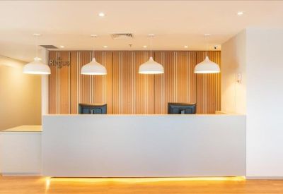 Bright reception desk with warm wooden wall panels and pendant lights.