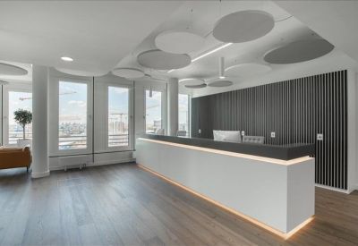 Bright reception area with a minimalist white desk and circular acoustic ceiling panels.