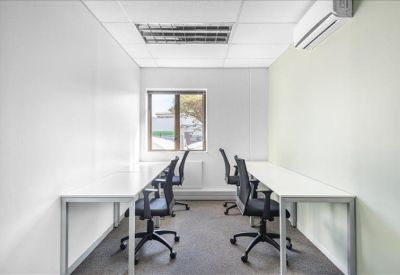 Modern white office suite with four workstations and a window view.