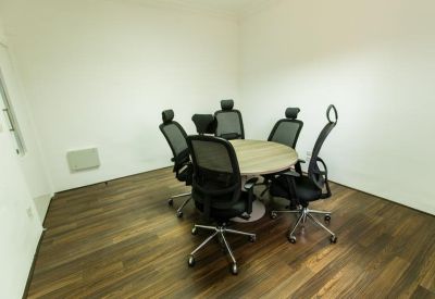Private office space featuring a round wooden table and five black ergonomic chairs.