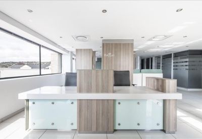 Professional reception desk with light wood paneling and glass accents.