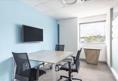 Bright private office suite with a four-person meeting table and wall-mounted screen.