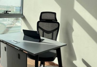 Single desk workstation with a tablet and ergonomic chair near a window.