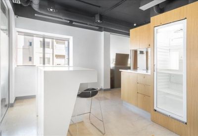 Modern breakroom kitchen with a sleek white breakfast bar and wood cabinetry.