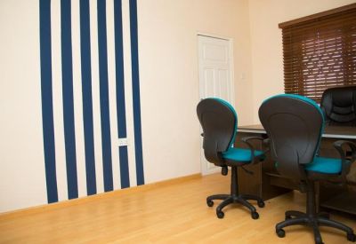 Office space with light wood floors, blue-backed chairs, and a striking blue and white striped feature wall.