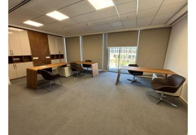 Spacious communal workspace featuring minimalist wooden desks and dark chairs.