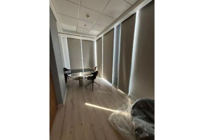 Small meeting room with wood floors and modern grey roller blinds.