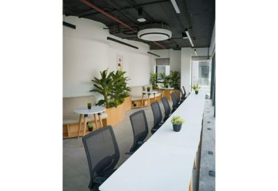 Coworking lounge with long white tables and indoor planters.