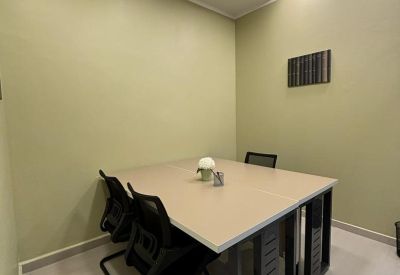 Small meeting room with a square table and black chairs against pale green walls.