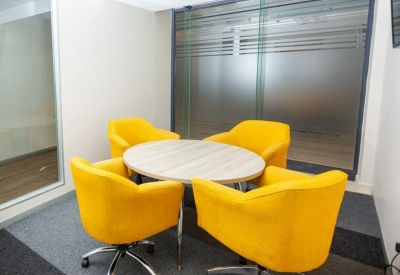 Private breakout room featuring four yellow upholstered armchairs around a circular table.