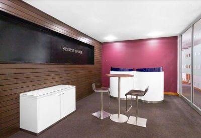 Modern business lounge with a wood-paneled wall, magenta accent wall, and high bistro-style seating.