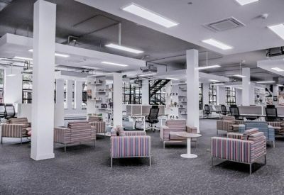 Spacious communal lounge featuring striped armchairs and modern white pillars.
