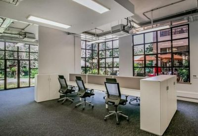 Modern open-plan office with three workstations and large grid windows.