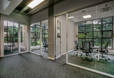 Private glass-walled meeting room with ergonomic black chairs and large windows.